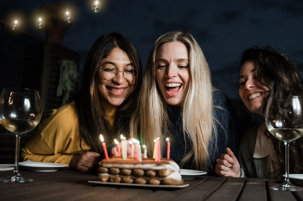 Happy multiracial people celebrating birthday party with cake and candles