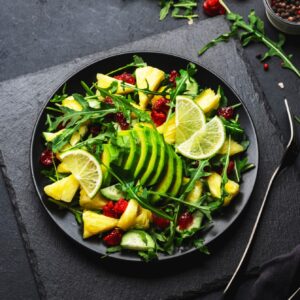 Fresh vegan salad with pineapple, arugula, avocado and dried cranberry