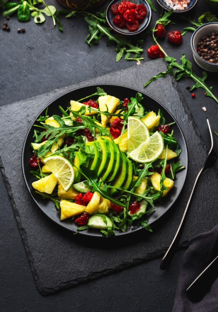 Fresh vegan salad with pineapple, arugula, avocado and dried cranberry